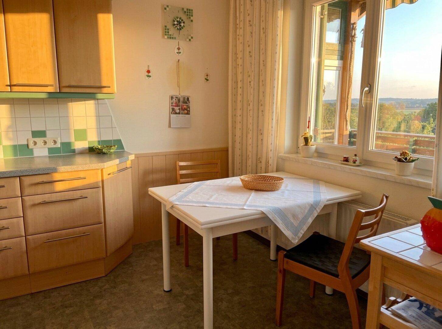 Gemütliche Wohnküche mit Esstisch, Holzschränken und weitem Ausblick.