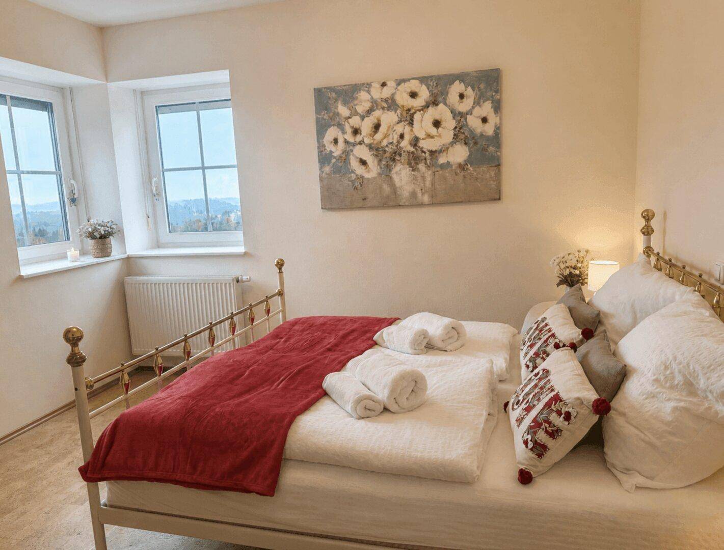 Gemütliches Schlafzimmer mit Metallbett und floralem Wandbild, bietet einen ruhigen Rückzugsort.