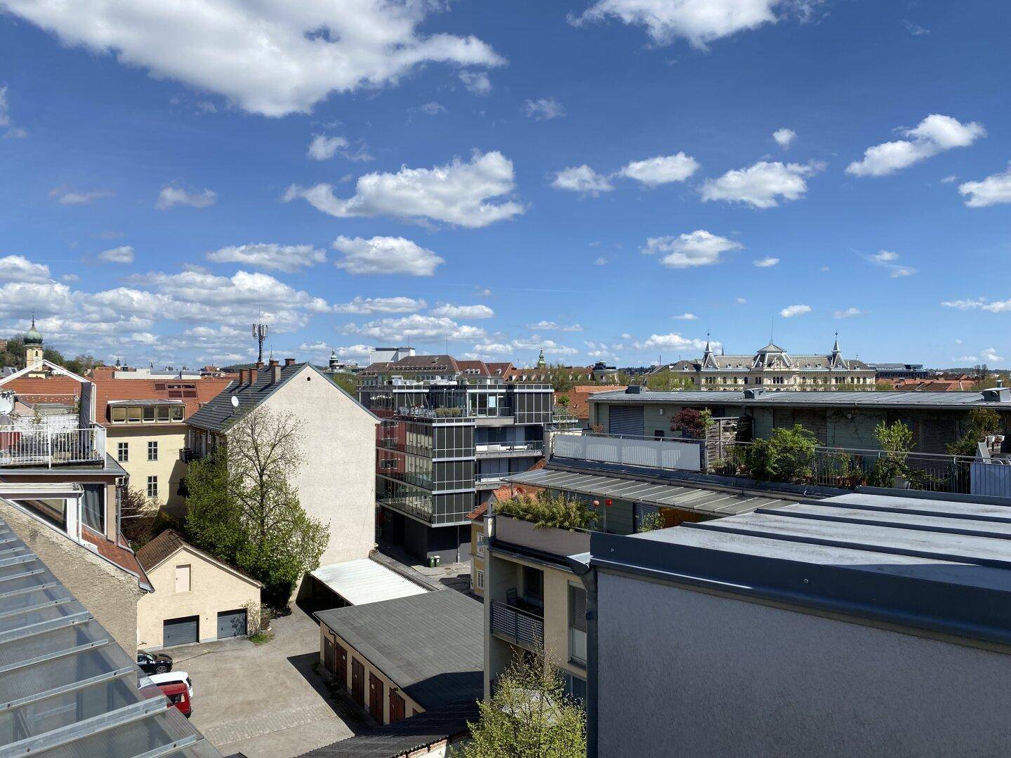 Panoramablick über die Dächer der Stadt unter einem blauen Himmel mit weißen Wolken.