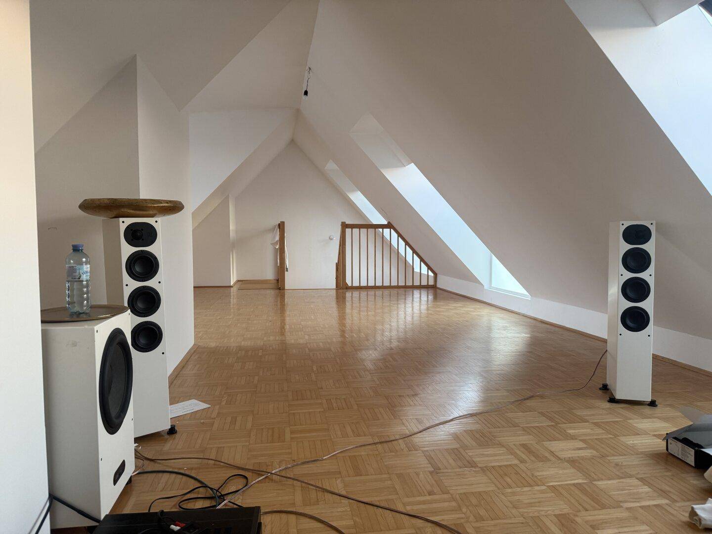 Geräumiges Dachgeschoss-Wohnzimmer mit Parkettboden, hohen Decken und großen Dachfenstern.