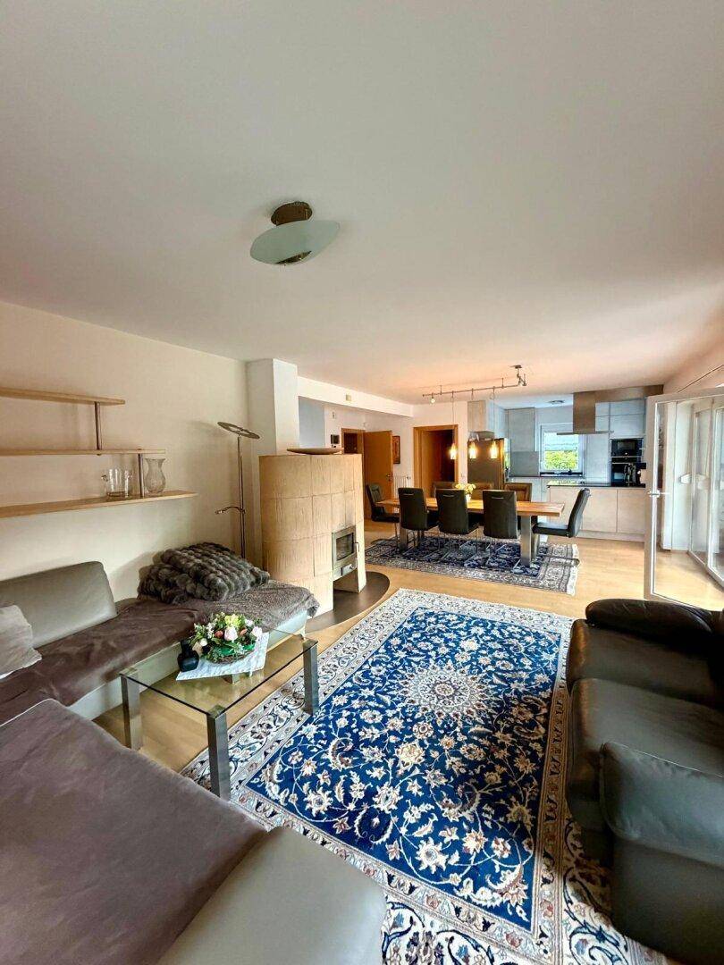 Gemütlicher Wohnbereich mit Sofas, Kaminofen und offenem Übergang zum Ess- und Küchenbereich.