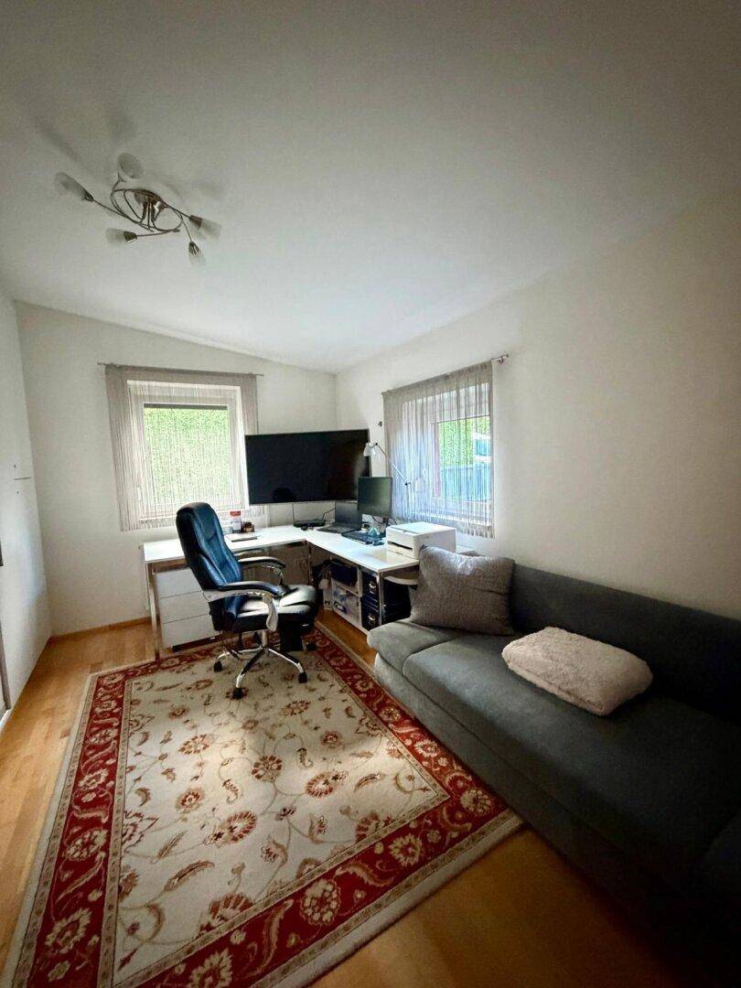 Funktionales Büro mit Schreibtisch, Sofa und Holzboden, ideal für Home-Office.