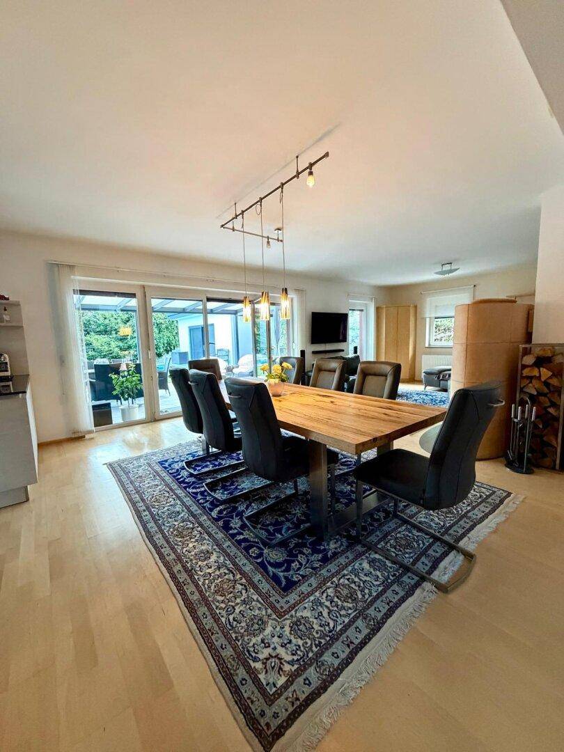Heller Essbereich mit Holztisch, Teppich und Zugang zur Terrasse, offen zum Wohnzimmer.