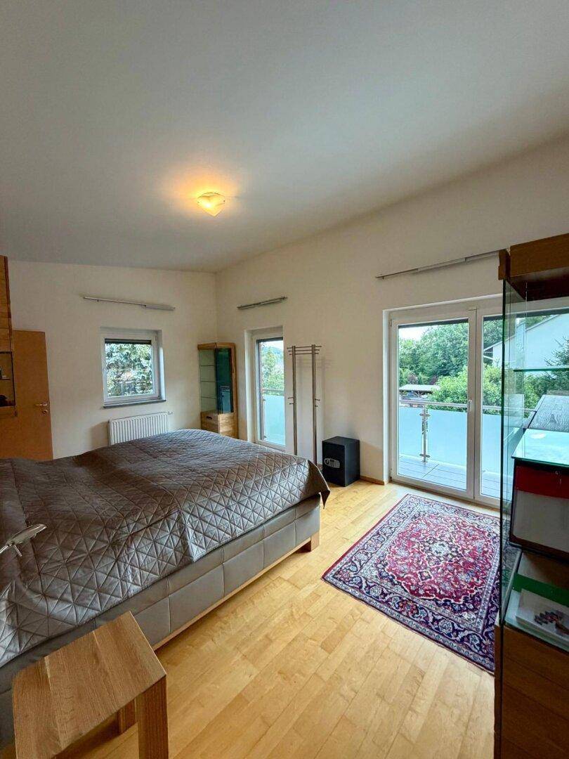 Geräumiges Schlafzimmer mit Doppelbett, Holzboden und direktem Zugang zum Balkon.