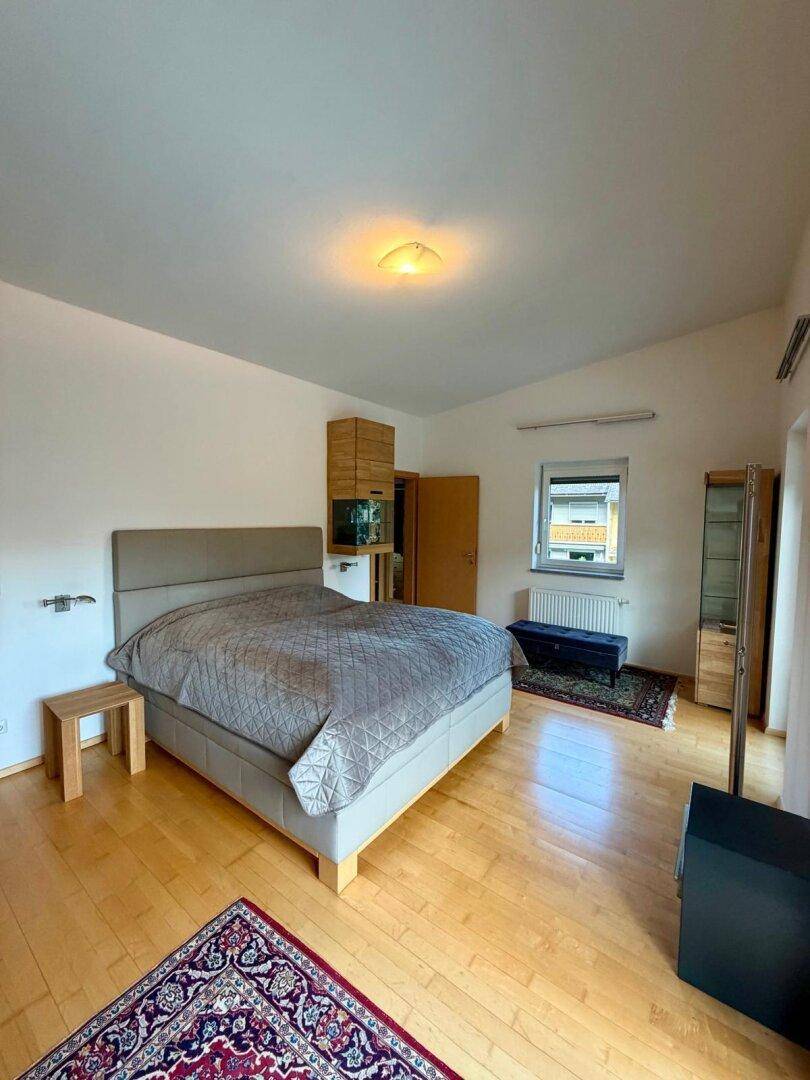 Helles Schlafzimmer mit großem Bett, Holzboden und Fenster für viel Tageslicht.
