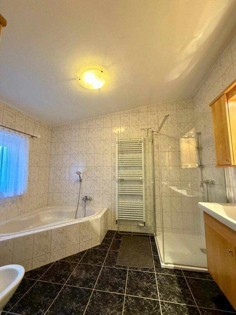 Badezimmer mit Eckbadewanne, Duschkabine, Bidet und beheiztem Handtuchhalter.
