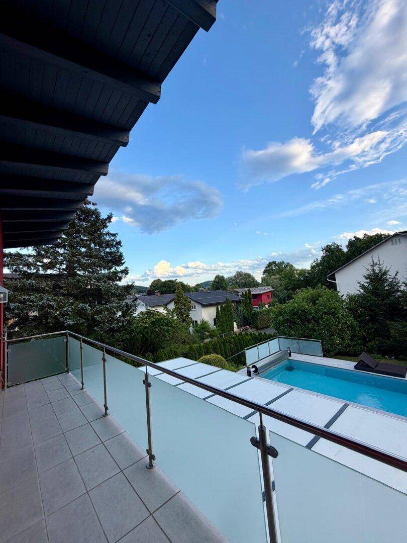 Geräumiger Balkon mit Glasgeländer bietet einen weiten Blick auf den Pool und die Umgebung.
