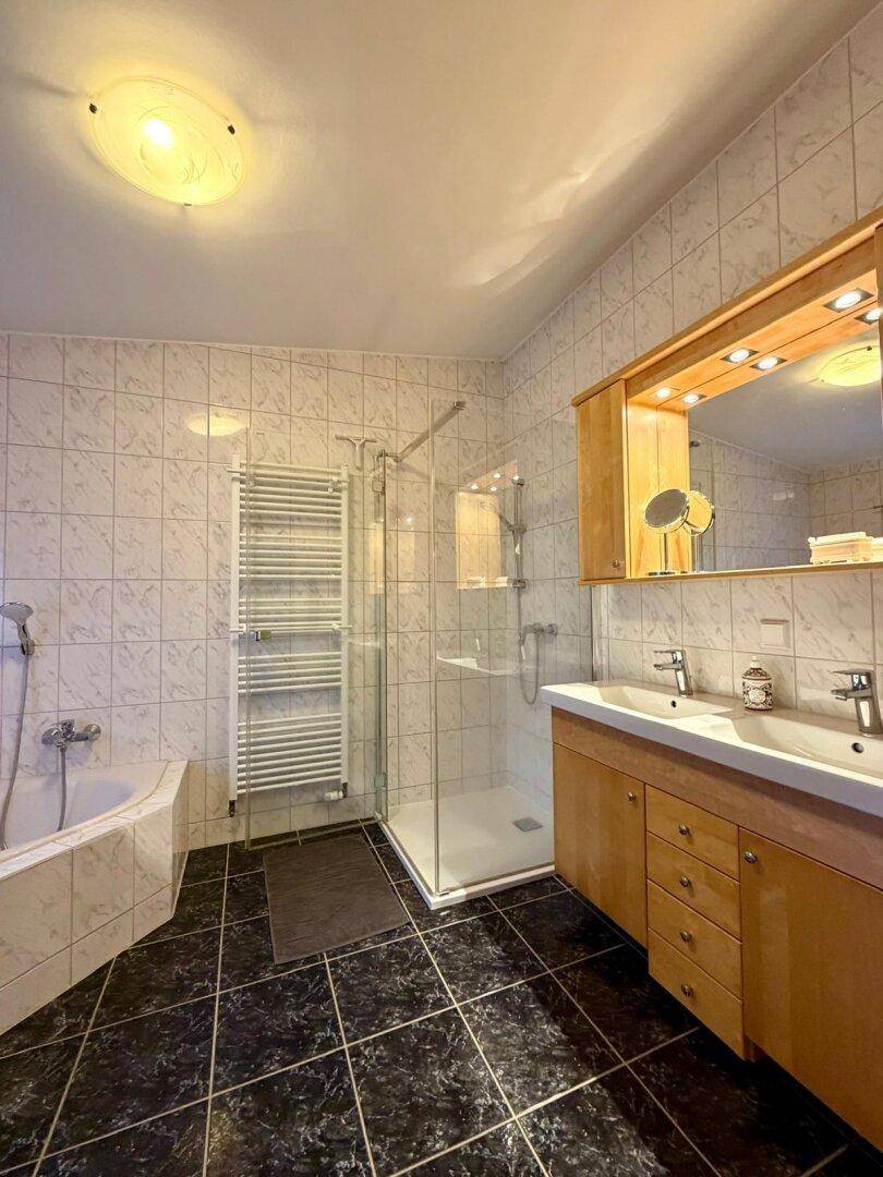 Modernes Badezimmer mit Eckbadewanne, Duschkabine und Doppelwaschbecken mit Spiegelschrank.