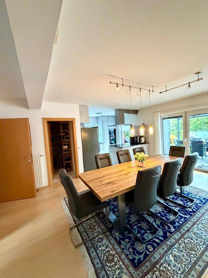 Geräumiger Essbereich mit großem Holztisch und Zugang zur modernen Küche.