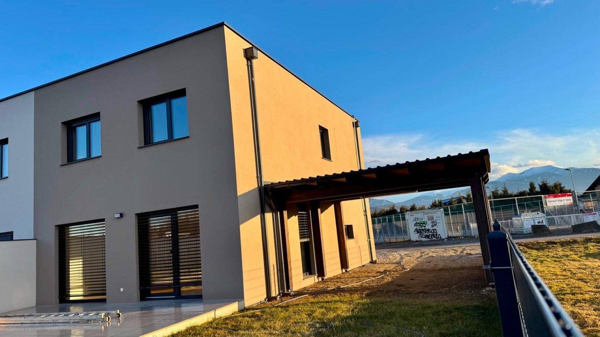 Moderne Architektur des Hauses mit großen Fenstern und Carport unter blauem Himmel.