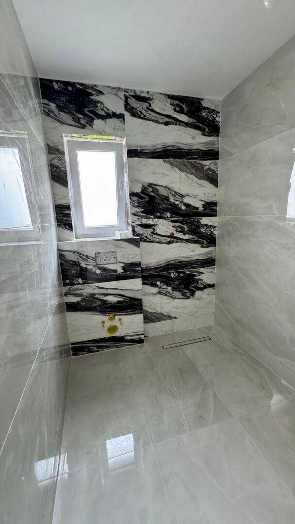Modernes Badezimmer mit kontrastreichen Marmorfliesen und einem Fenster für natürliches Licht.