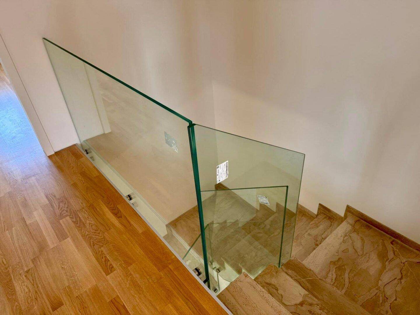 Blick von oben auf die moderne Treppe mit Glasgeländer und Natursteinstufen.