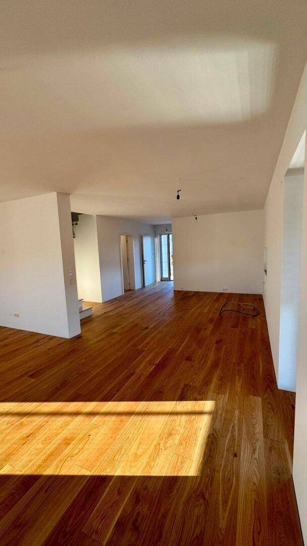 Heller, leerer Raum mit hochwertigem Holzparkettboden und weißen Wänden, bereit zum Einzug.