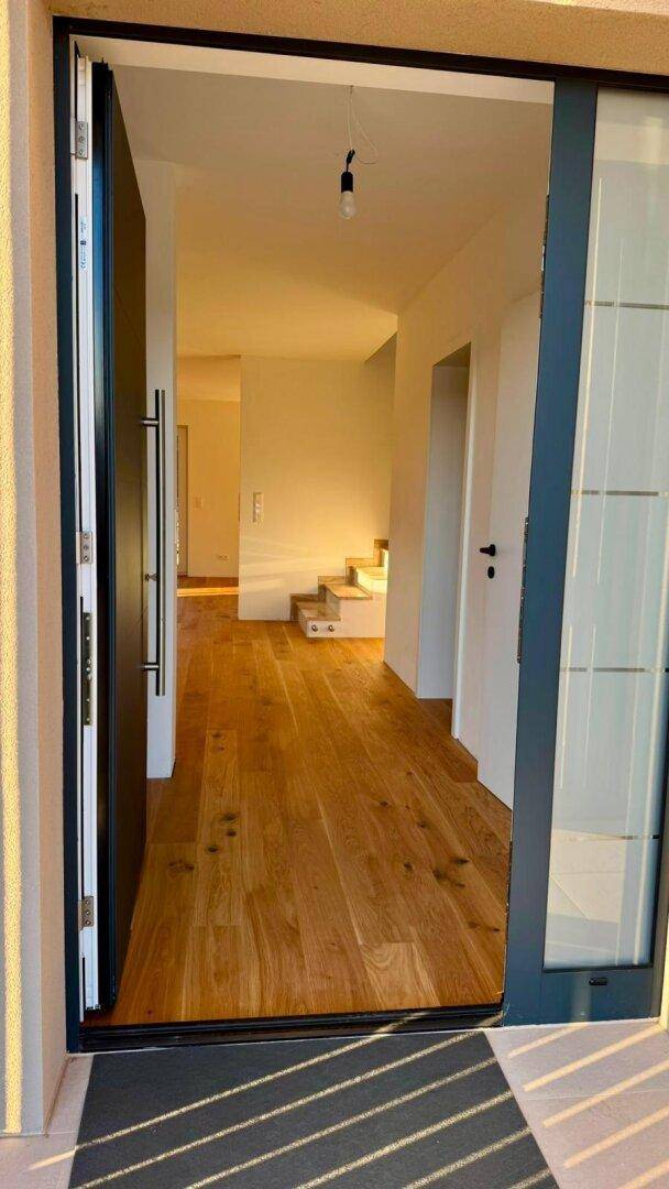 Heller Eingangsbereich mit Holzboden, der den Blick auf den Flur und die Treppe freigibt.