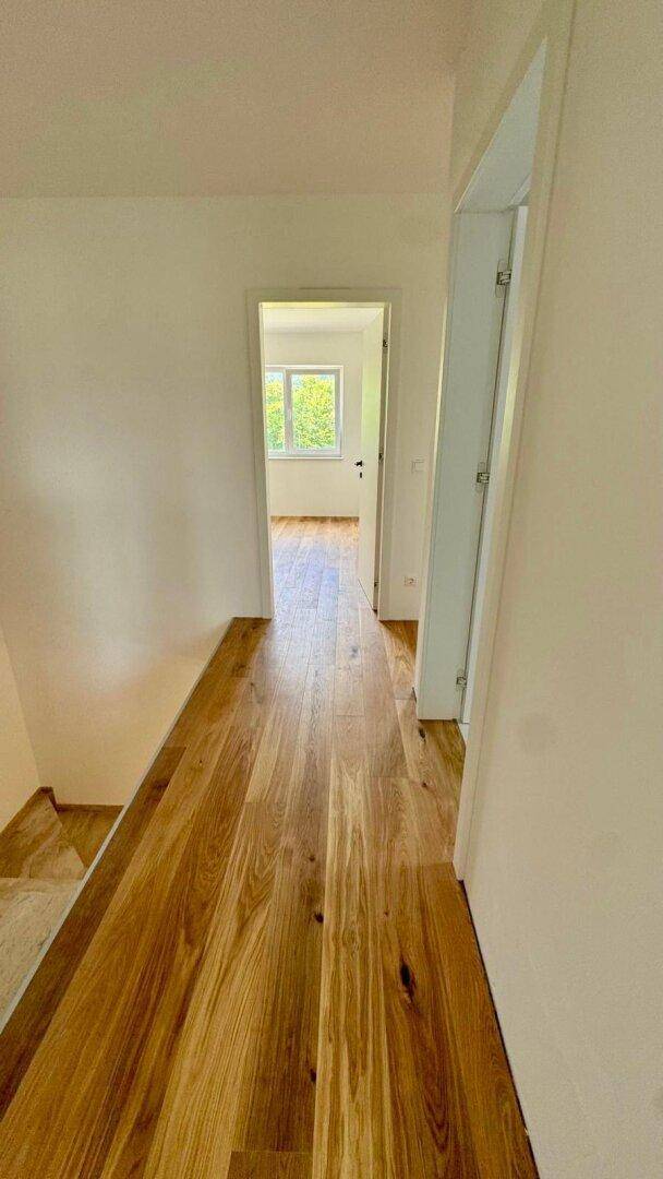 Langer, heller Flur mit Holzboden, der zu weiteren Zimmern im Obergeschoss führt.
