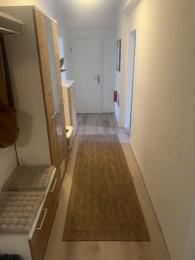 Heller Flur mit Garderobe, Spiegel und Laminatboden.