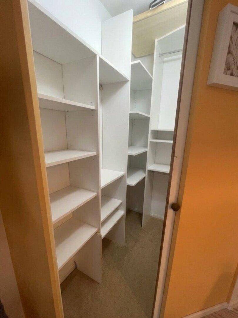 Geräumiger begehbarer Kleiderschrank mit vielen Regalen und Aufbewahrungsmöglichkeiten.