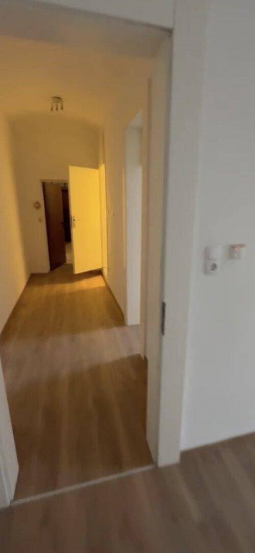 Langer, heller Flur mit Laminatboden, der zu weiteren Räumen führt.