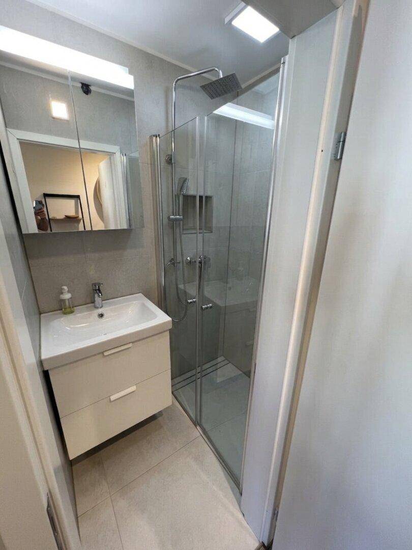 Modernes Badezimmer mit begehbarer Dusche, Hänge-Waschtisch und Spiegelschrank.