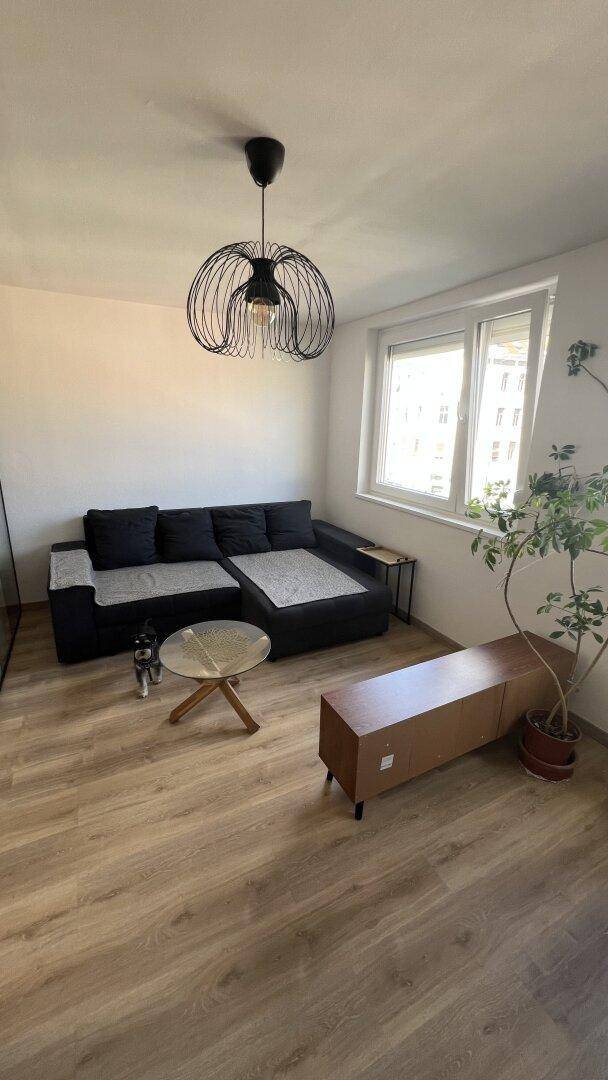 Gemütliches Wohnzimmer mit Ecksofa, Couchtisch und großem Fenster.