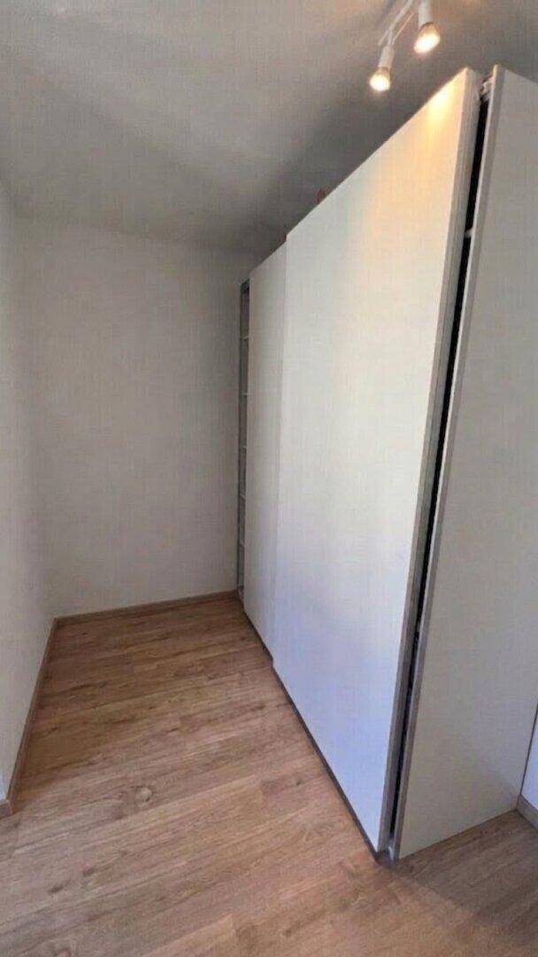 Kleiner Raum mit Laminatboden und Schrankwand, möglicherweise als Ankleide oder Abstellraum.