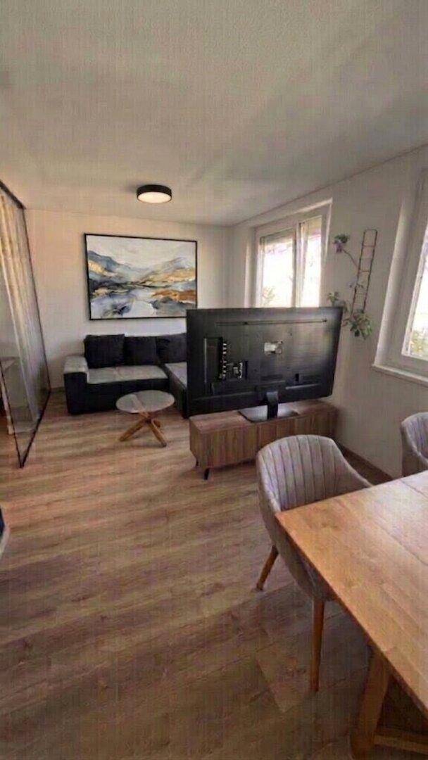 Offener Wohn- und Essbereich mit Fernseher, Sofa und Esstisch.