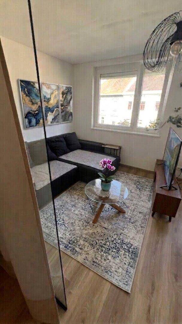 Wohnzimmer mit Sofa, Teppich, Couchtisch und Blick nach draußen.