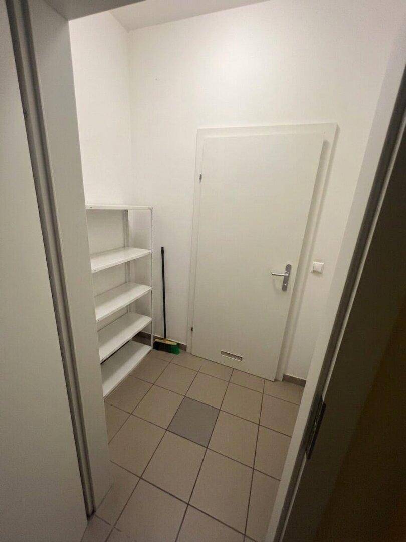 Praktischer Abstellraum mit Regalen für zusätzlichen Stauraum und gefliestem Boden.