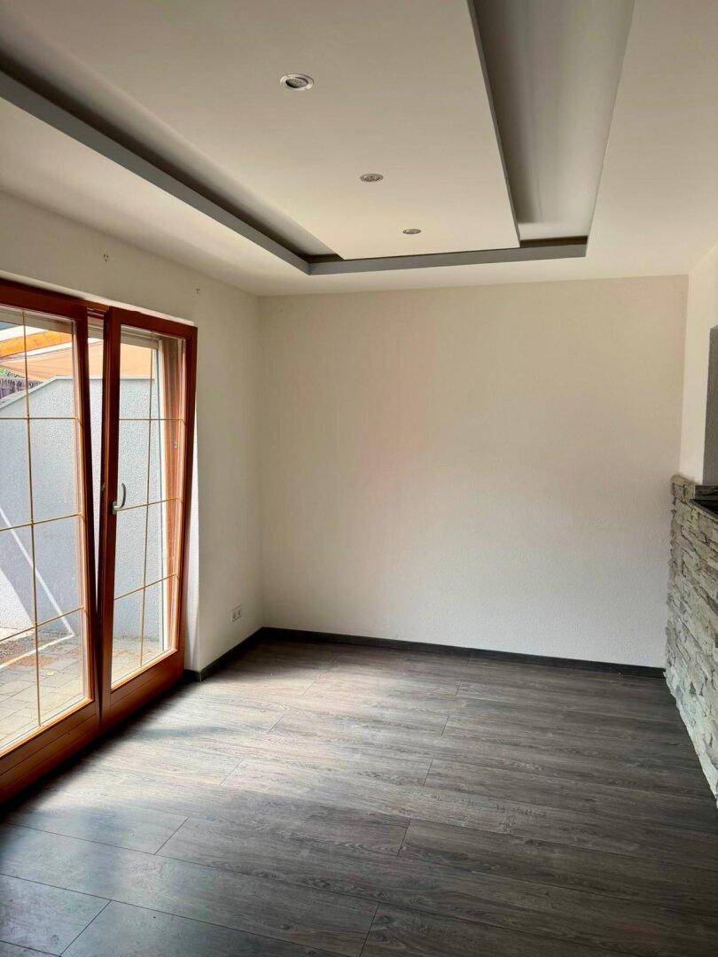 Helles Wohnzimmer mit großen Schiebetüren, die Zugang zur Terrasse und zum Garten bieten.