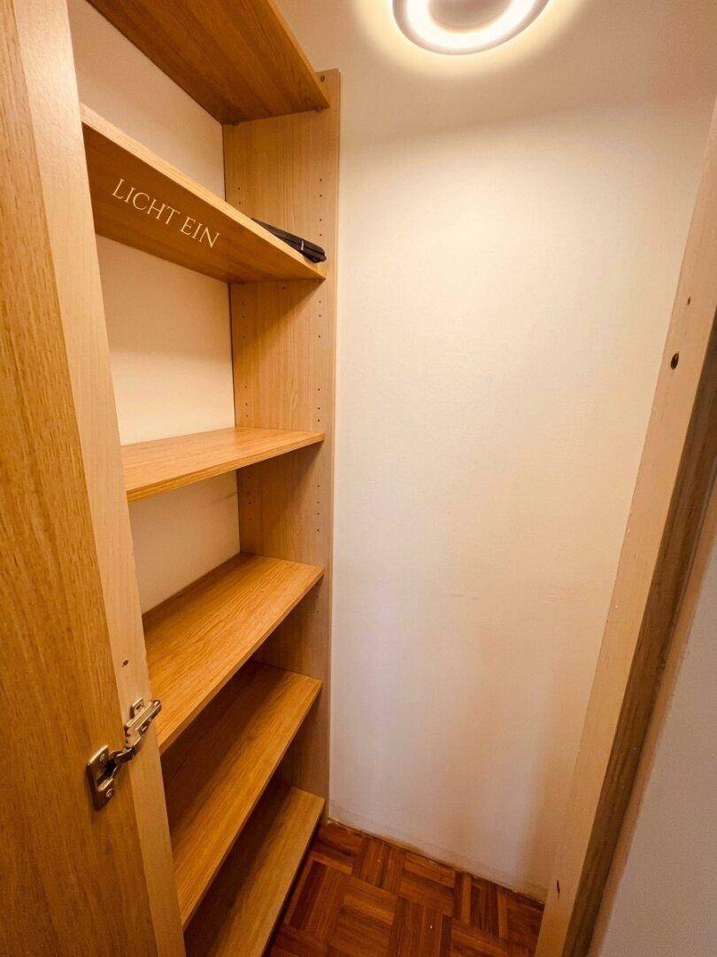Praktischer Abstellraum mit Holzregalen und Parkettboden, ideal für zusätzlichen Stauraum.