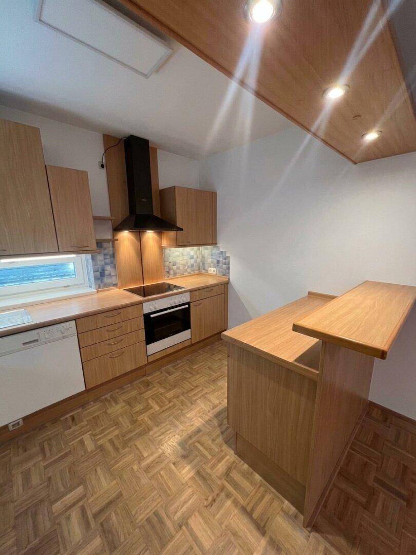 Funktionale Küche mit Holzschränken, integrierten Geräten und einer kleinen Frühstücksbar.