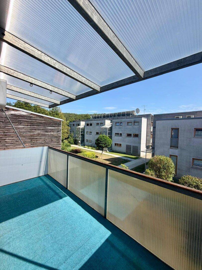 Geräumiger Balkon mit Überdachung und weitem Blick auf die Nachbarschaft.