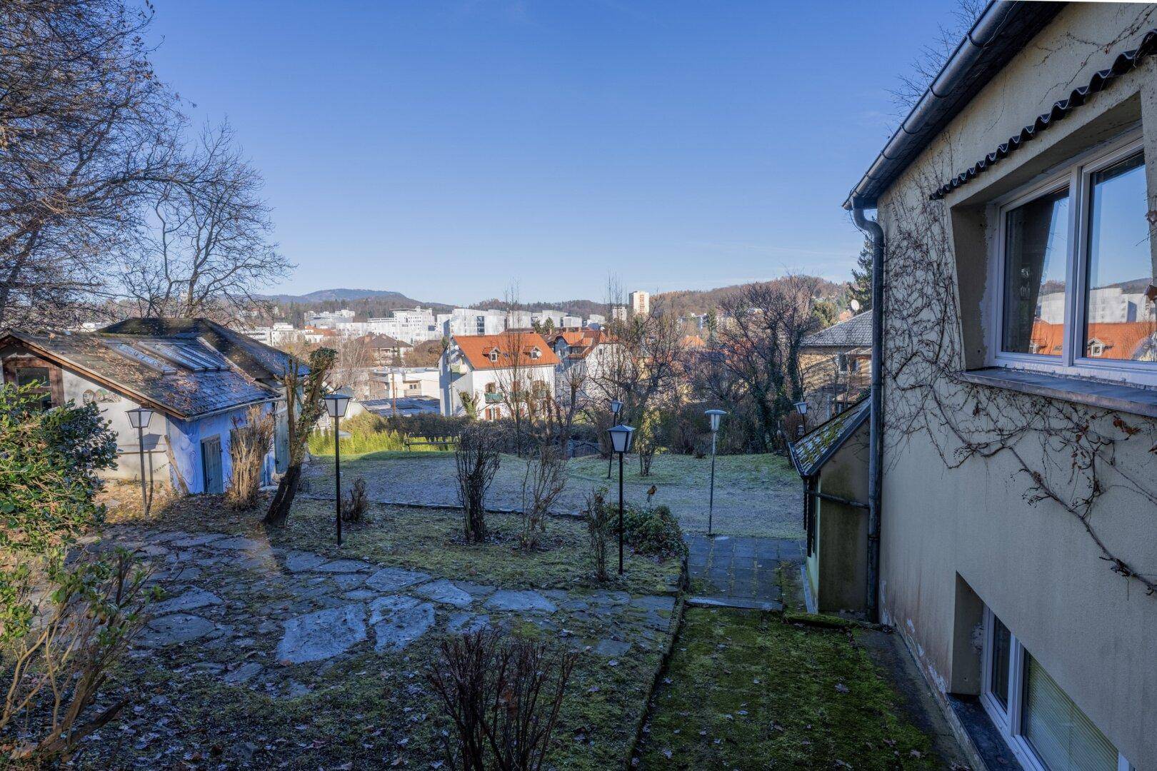 Blick über den Gartenbereich auf die umliegende Stadtlandschaft und die Hügel in der Ferne.