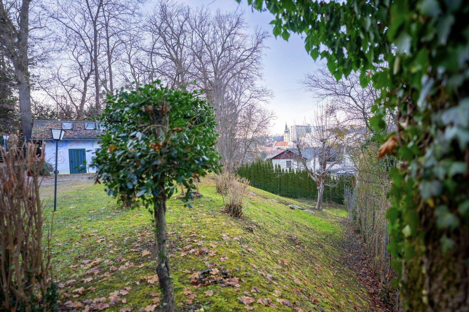 Gartenlandschaft mit gepflegten Pflanzen und weitem Blick über die Stadtkulisse.