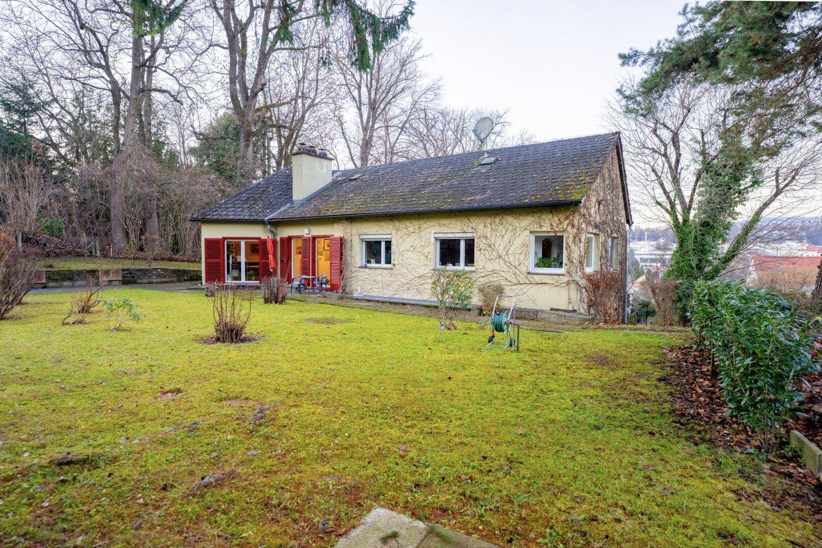 Rückansicht des Hauses mit großem Garten und Terrasse, umgeben von Natur.