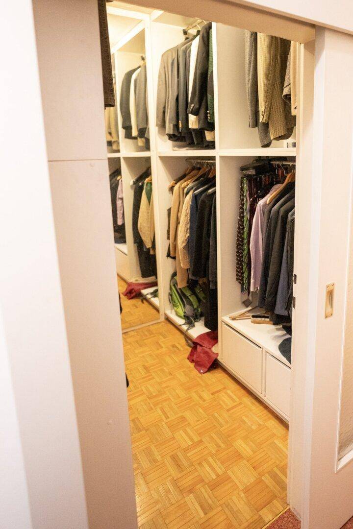 Geräumiger begehbarer Kleiderschrank mit viel Stauraum und Parkettboden.