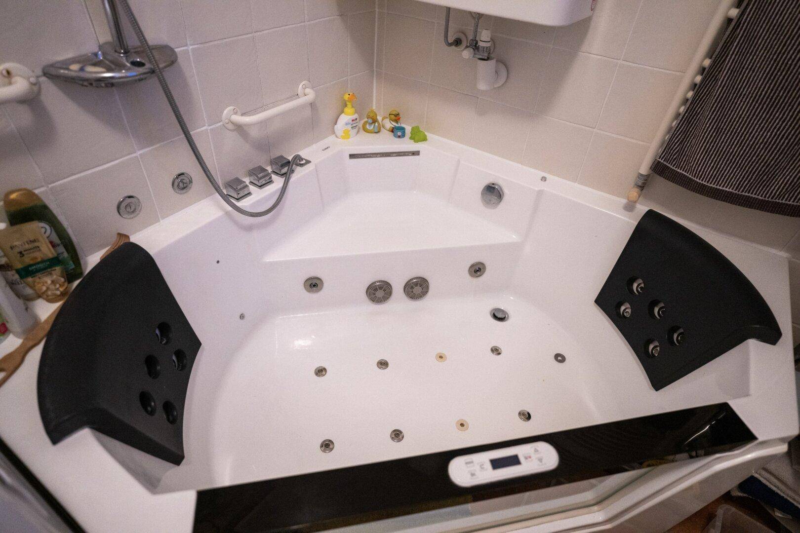 Nahaufnahme des modernen Eck-Whirlpools mit Massagedüsen im Badezimmer.