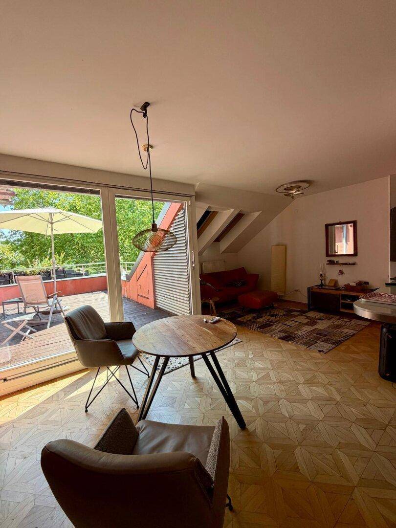 Helles Wohnzimmer mit Dachschrägen, Parkettboden und direktem Zugang zu einer großen Terrasse.