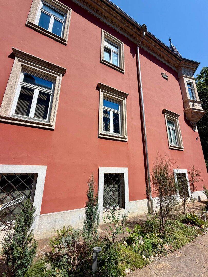 Historische Fassade eines Gebäudes in leuchtendem Rot mit vielen Fenstern.