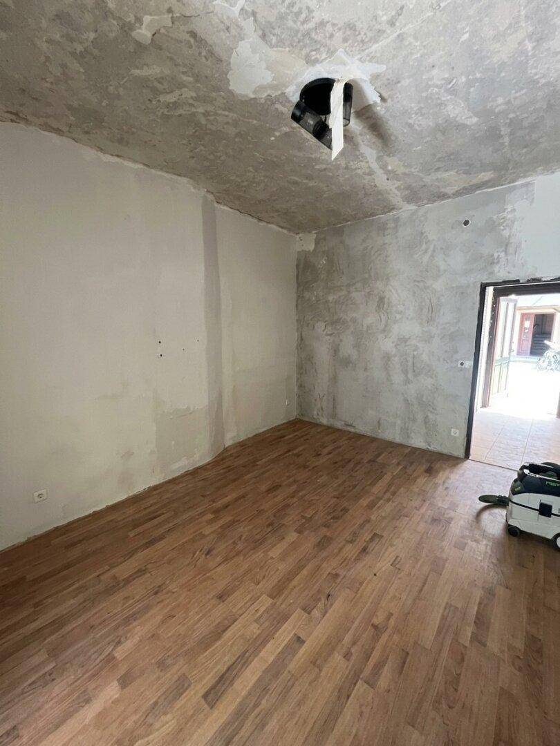 Raum in Renovierung mit neu verlegtem Holzboden und unfertigen Wänden.
