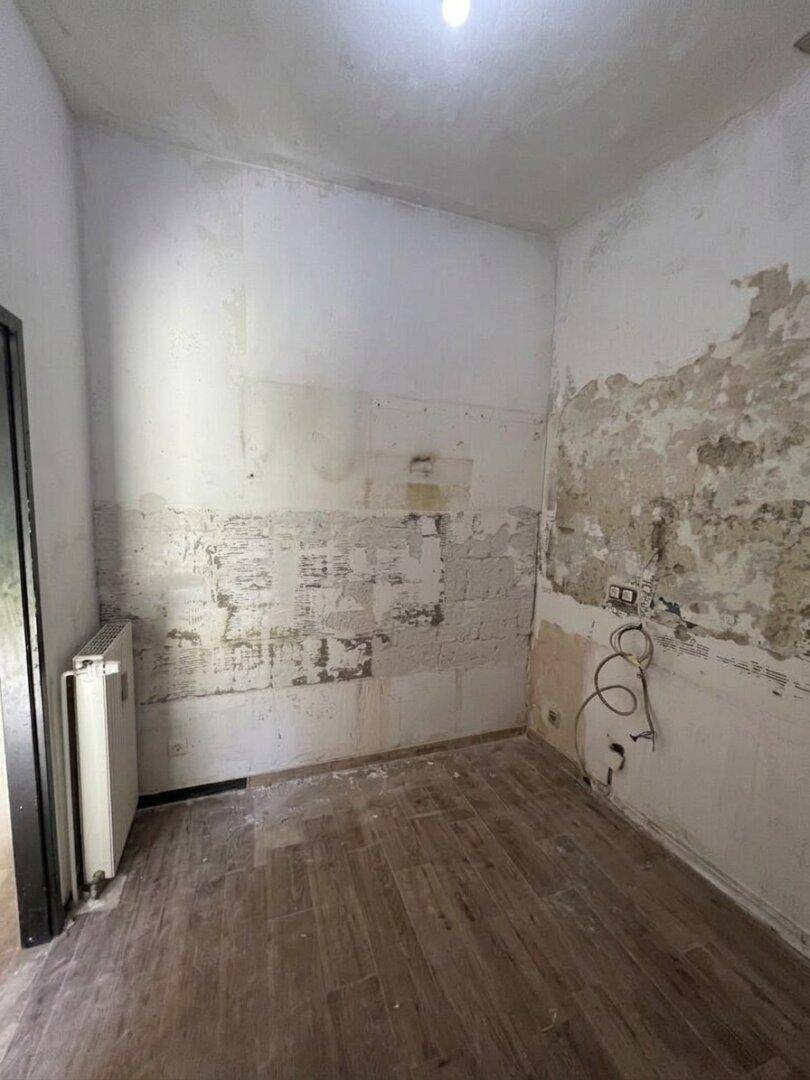 Raum in Renovierung mit Heizkörper und abblätternder Wandfarbe, bereit für den Ausbau.