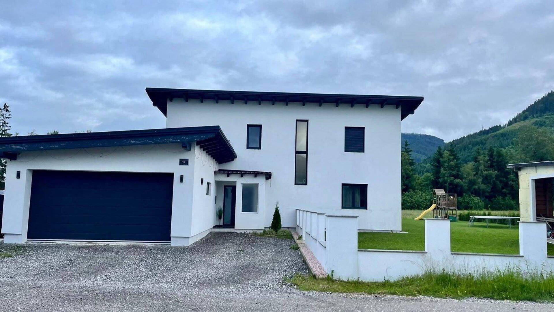 Modernes Einfamilienhaus mit integrierter Garage und gepflegtem Vorgarten in ländlicher Umgebung.