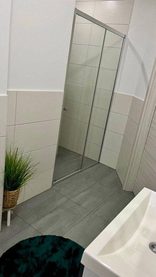 Modernes Gäste-WC mit Duschkabine, hellen Fliesen und minimalistischem Design.