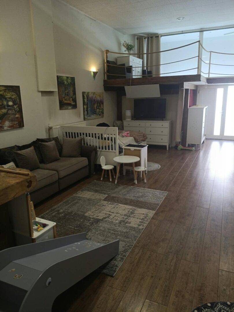 Geräumiges Wohnzimmer mit hoher Decke, Holzfußboden und einer Galerieebene.