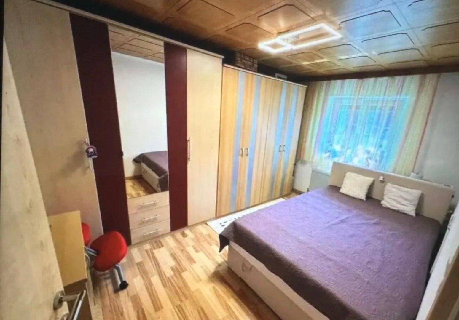 Schlafzimmer mit Doppelbett, Spiegelschränken und Holzdeckenverkleidung.