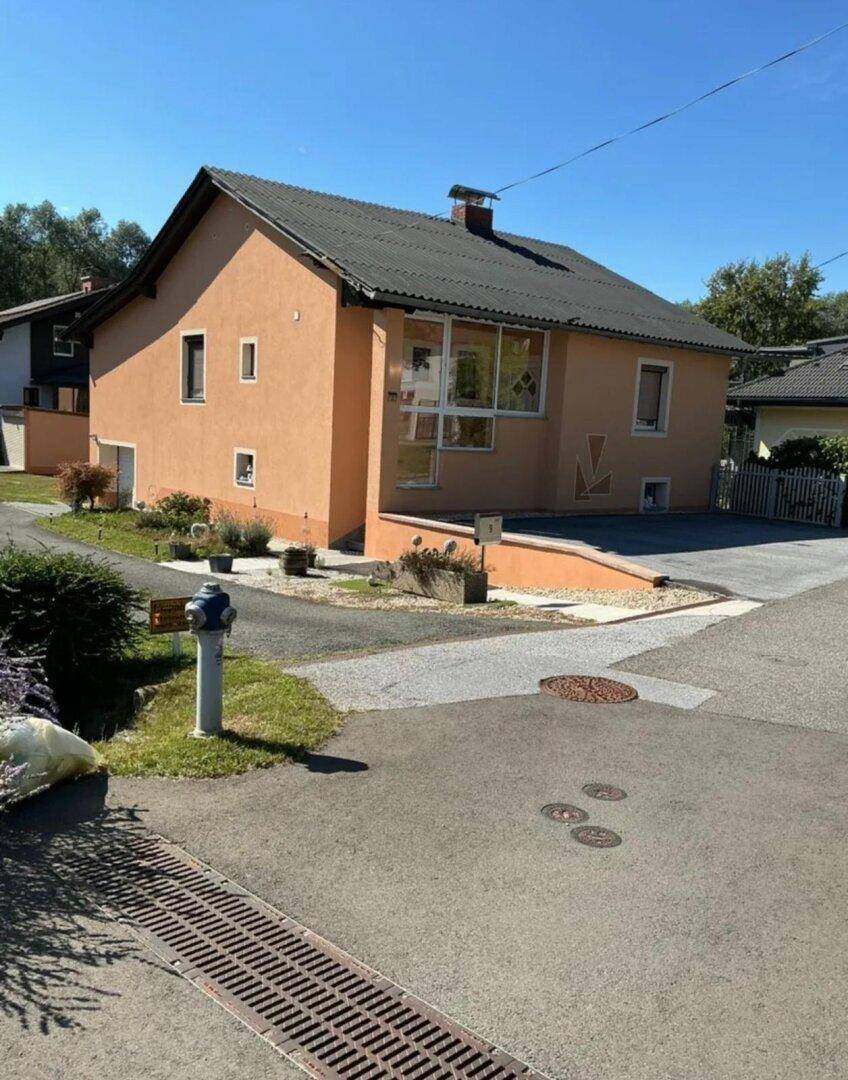 Einfamilienhaus mit oranger Fassade, Satteldach und gepflegter Außenanlage.