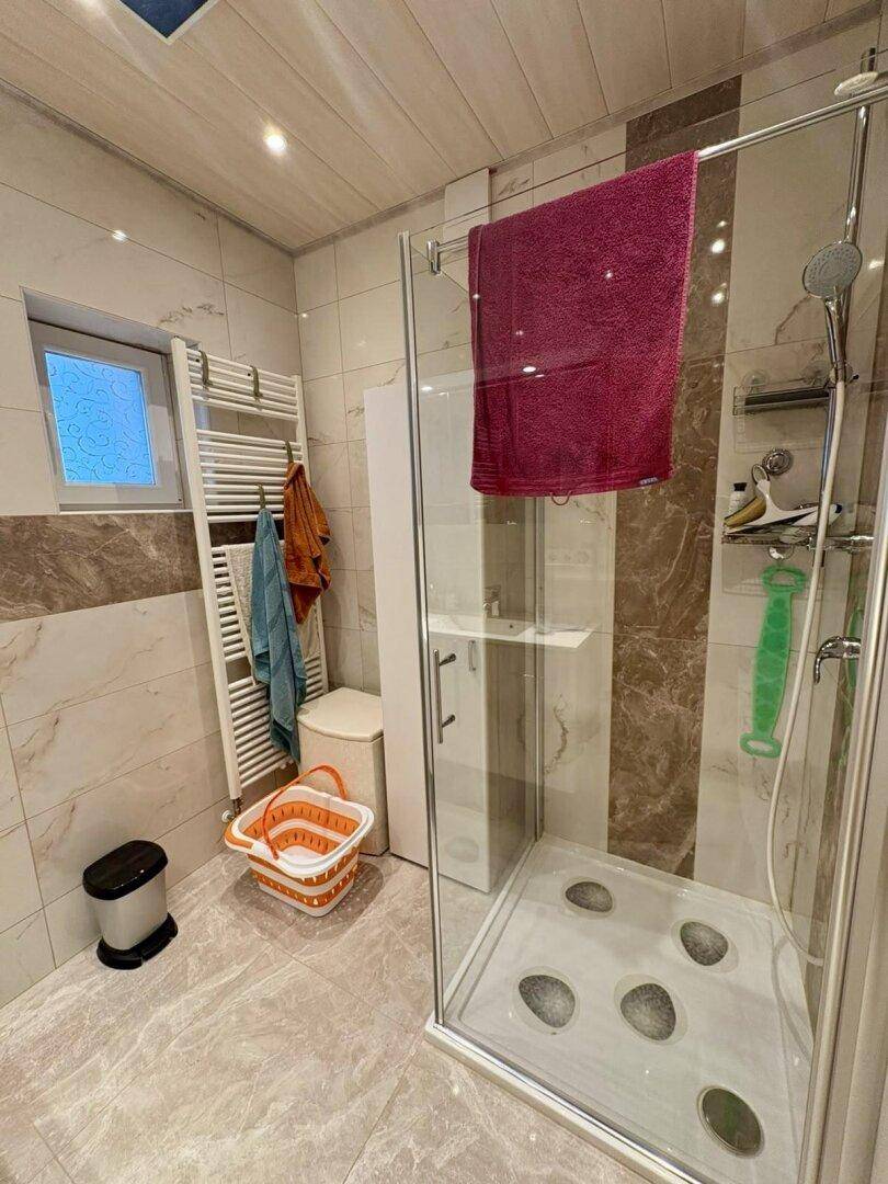 Modernes Badezimmer mit begehbarer Dusche, Fliesenboden und beheiztem Handtuchhalter.