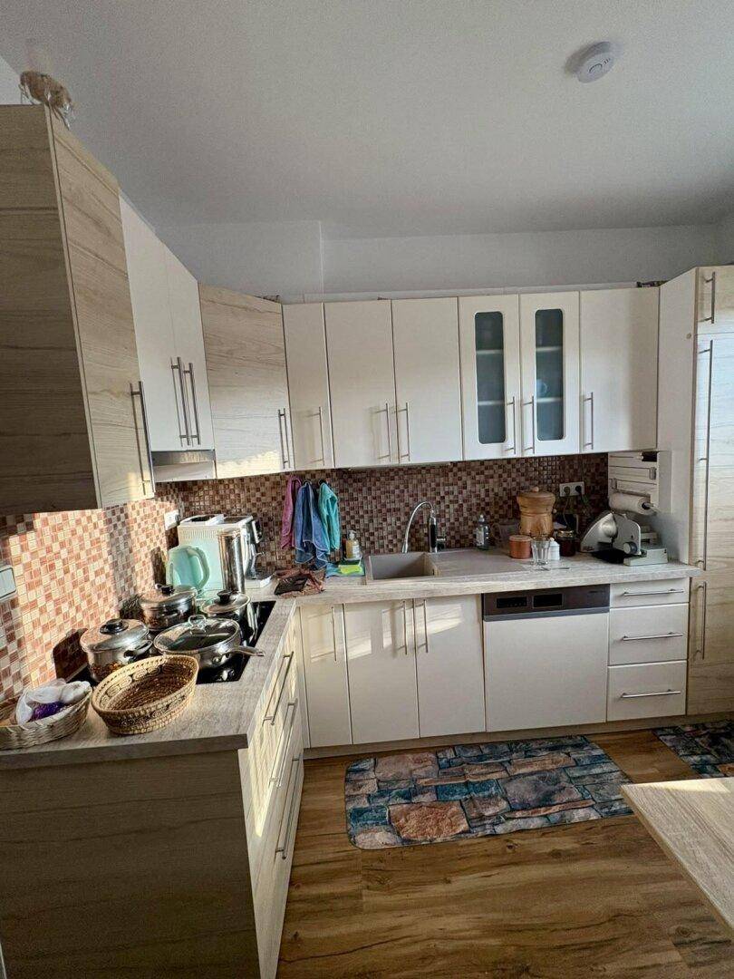 Funktionale Küche mit hellen Holzfronten, Fliesenrückwand und integrierten Geräten.