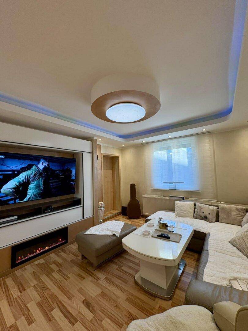 Stilvolles Wohnzimmer mit integriertem TV-Möbel, elektrischem Kamin und indirekter Beleuchtung.