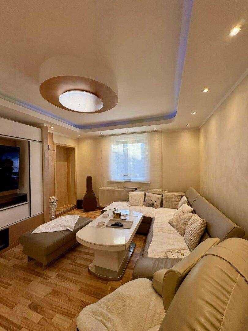 Gemütliches Wohnzimmer mit großem Ecksofa, Couchtisch und stimmungsvoller Deckenbeleuchtung.